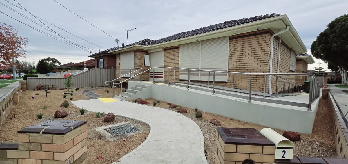 Brick clinic with a ramp, handrails and a landscaped concrete path
