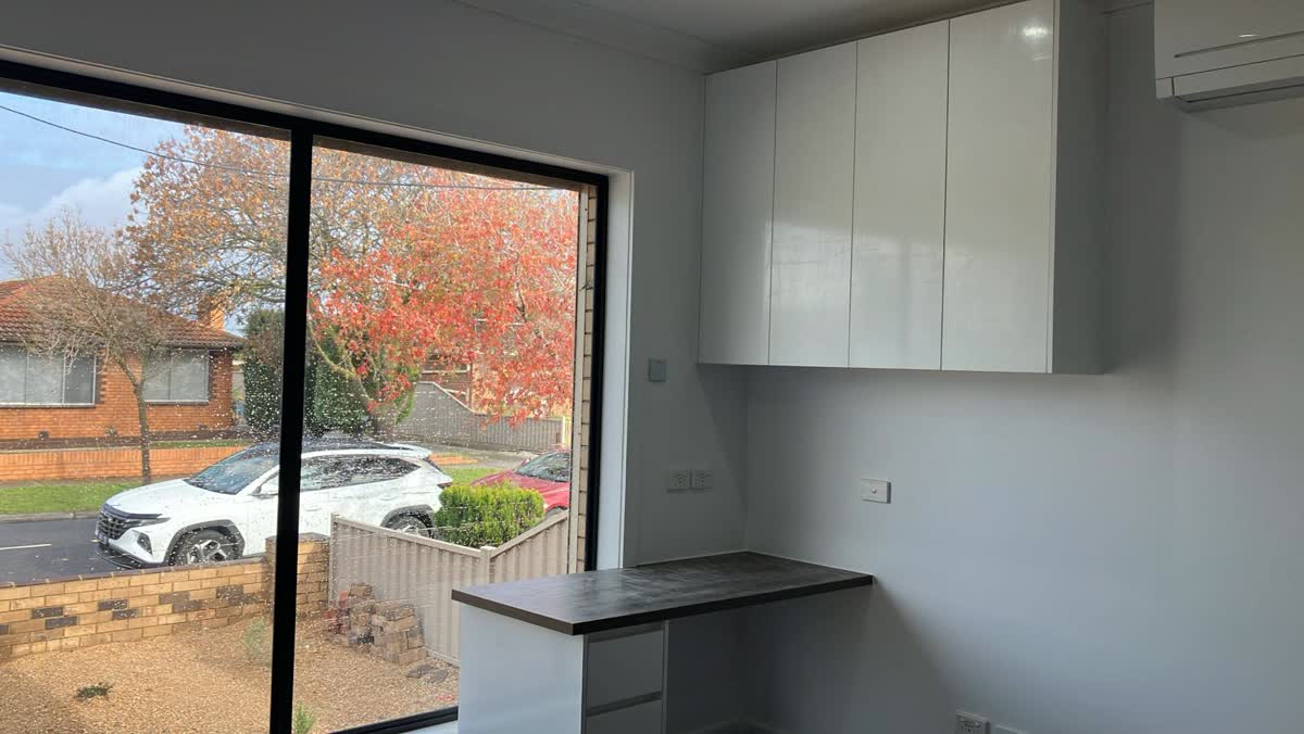Kitchenette with white cupboards and a window
