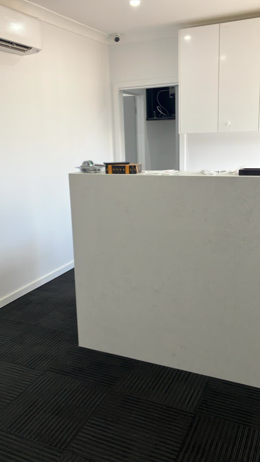 Reception desk with a white bench and carpet tiles