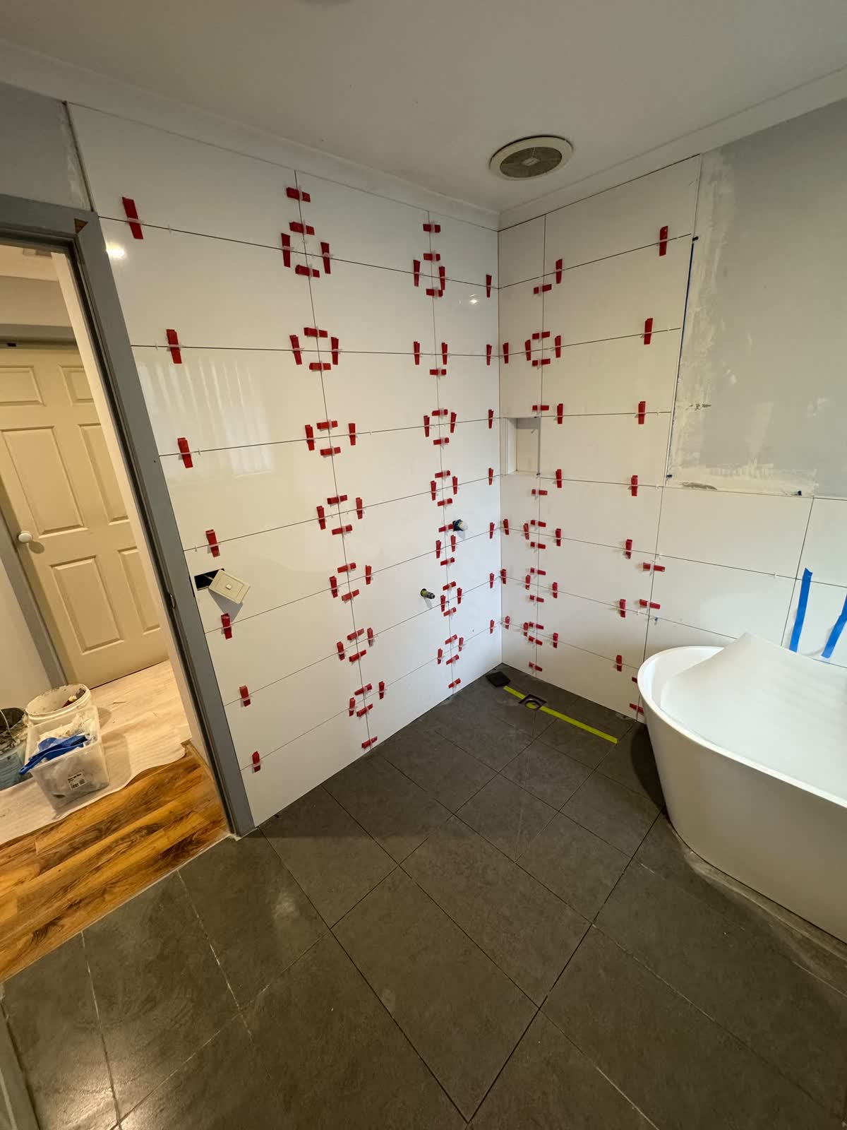 Large white wall tiles going up with levelling clips