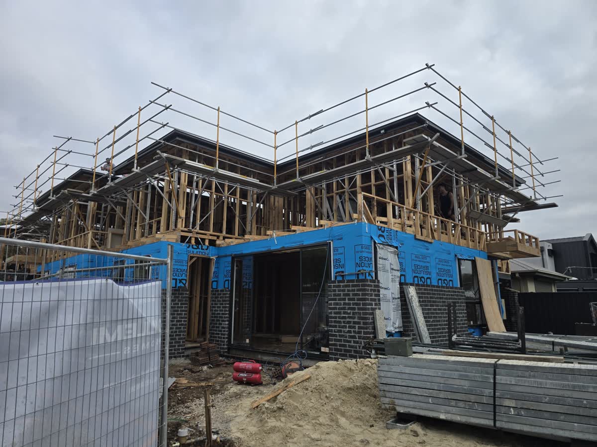 Two-storey townhouse frames with scaffold and edge protection around the roof