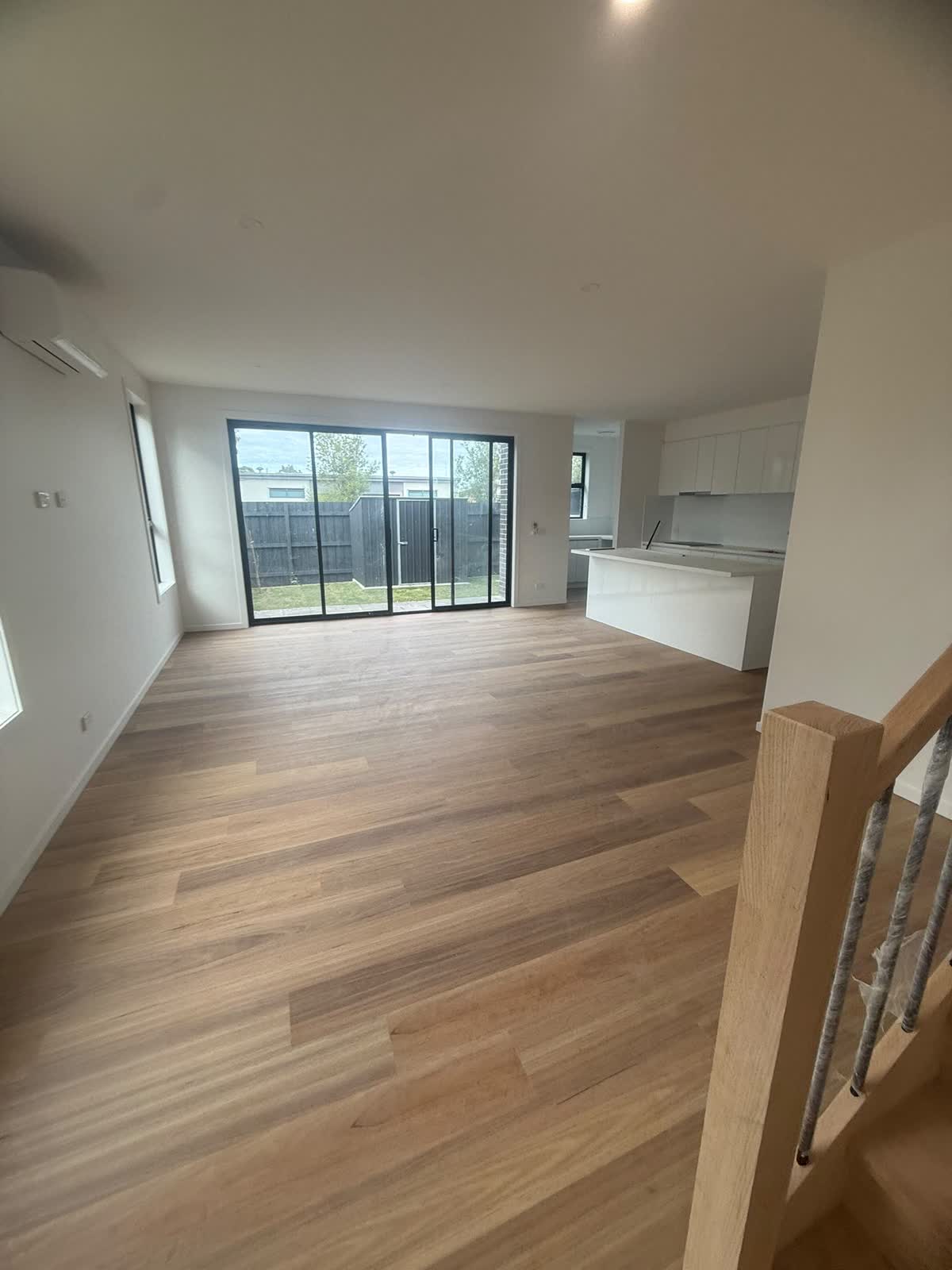 Open living room with timber floors, a kitchen and sliding doors to the yard