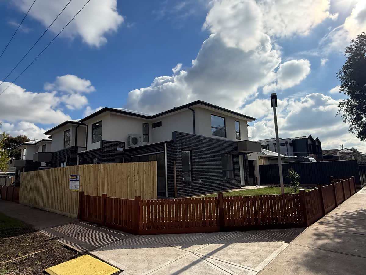 Three finished double-storey townhouses on a corner block with timber fences