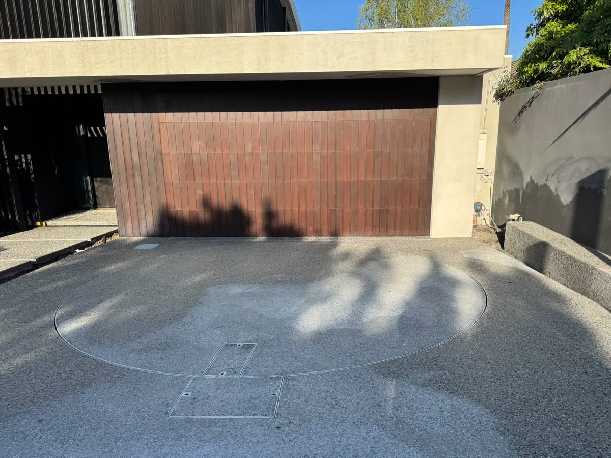 Finished exposed aggregate driveway with a circular turntable in front of a timber garage door