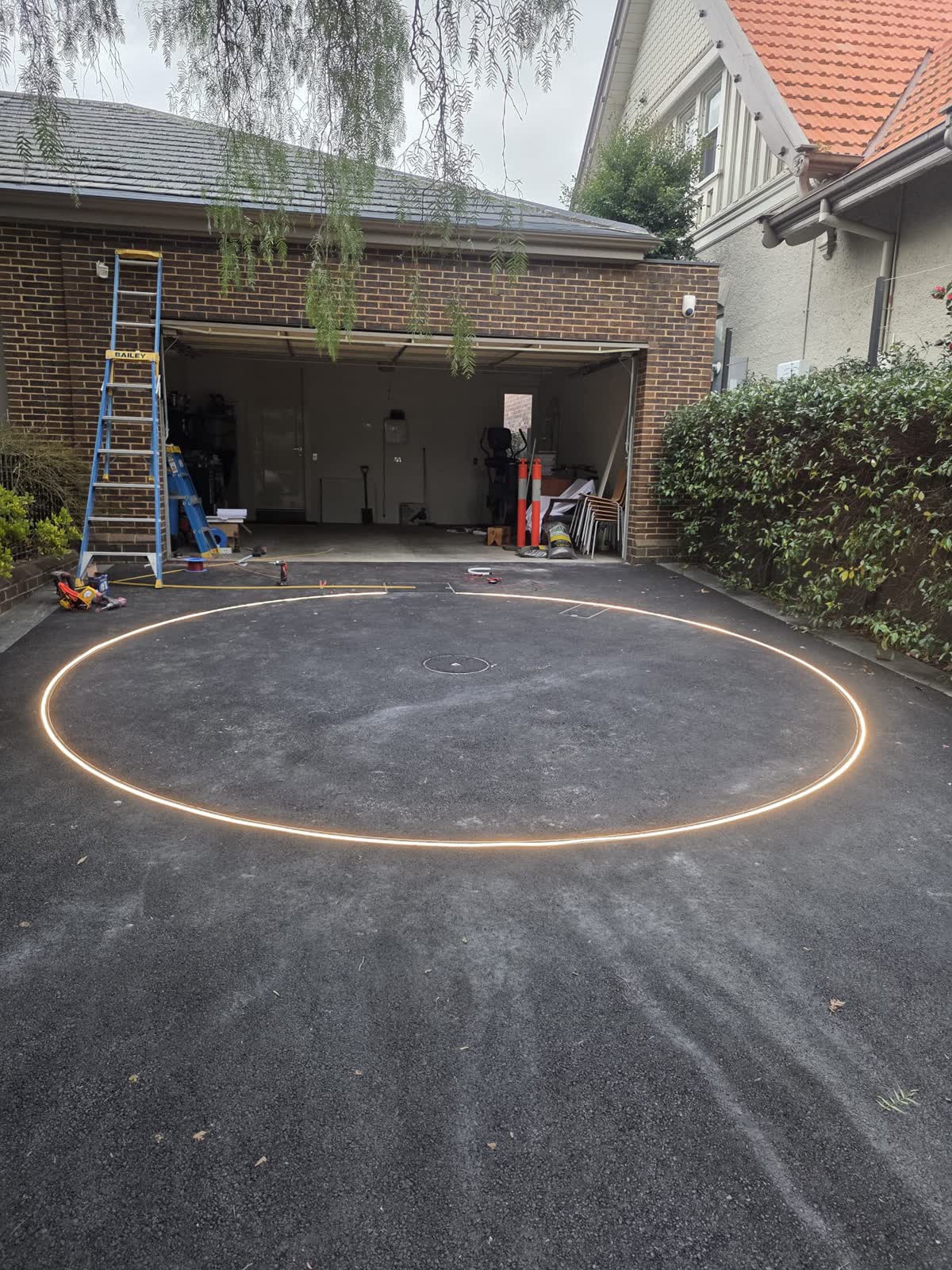 Asphalt driveway with a lit ring marking the circular turntable in front of a garage